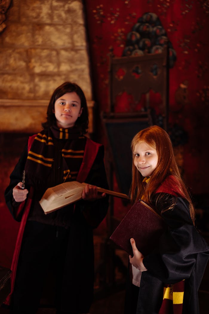Two students in wizard costumes holding a wand and book in a magical setting.