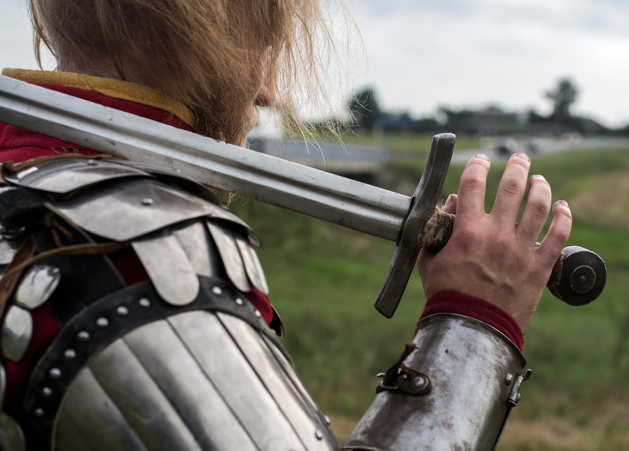 Close-up of a medieval knight holding a sword in armor outdoors, embodying historic warfare.